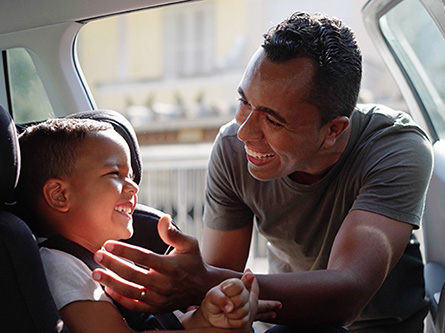 Father puts his male child in a car seat